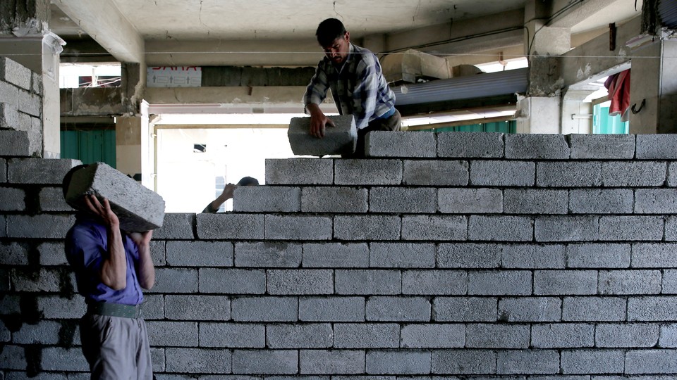 Two workers lay stones in order to rebuild a shop that was destroyed during fighting between Iraqi forces and Islamic state fighters in Mosul, Iraq.