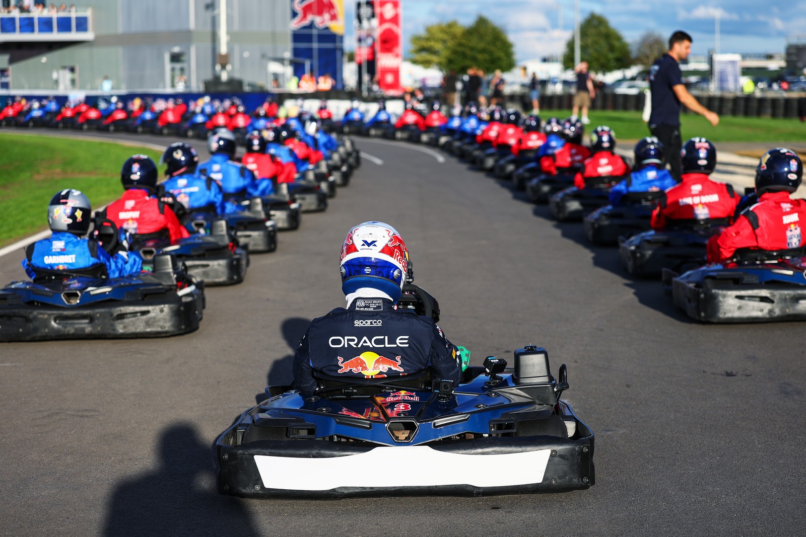 Dozens of drivers sit in low-slung go-karts on a track, before a race.