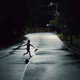 a child runs through a street at night, his arms outstretched