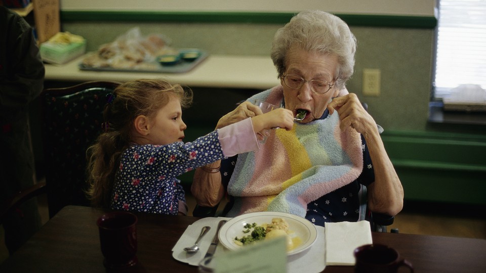 A toddler feeding an elderly woman from a fork.