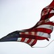 A tattered American flag flying atop a flagpole with a bronze-colored topper
