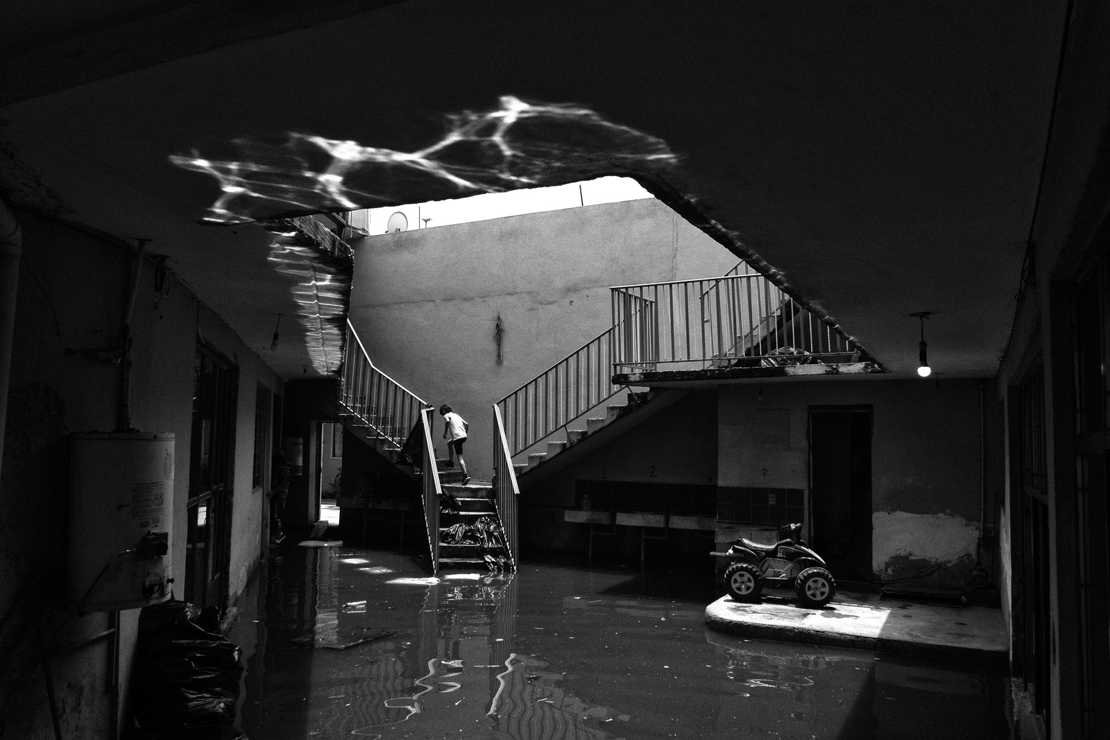 A child runs up to the second floor of a partially submerged home during a flood.