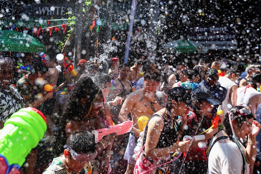 A crowd of people spray each other with water guns.