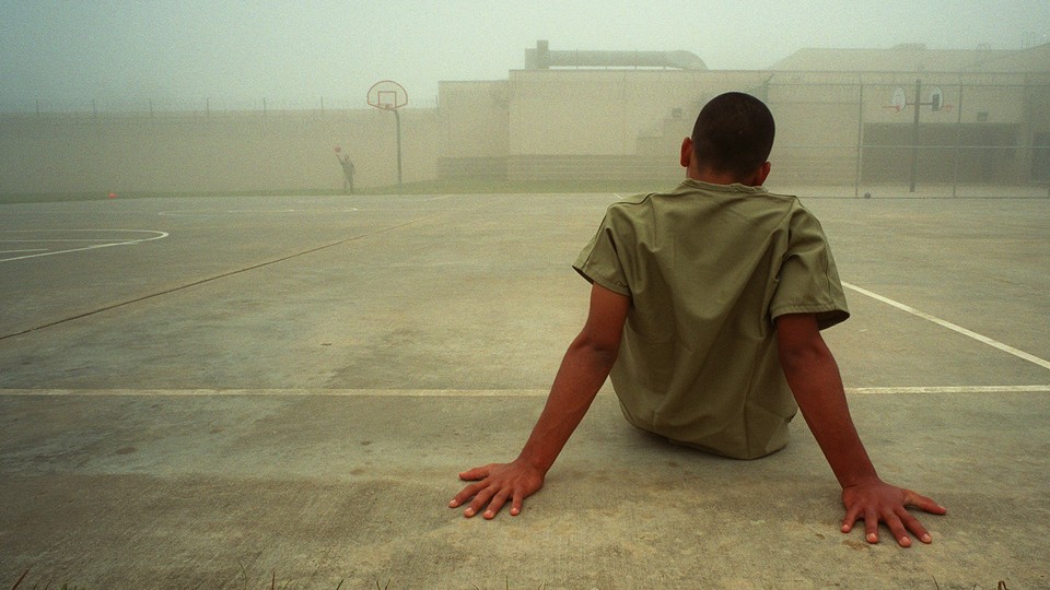 A boy sits in an outdoor recreation area at the Liberty County Jail in Texas.