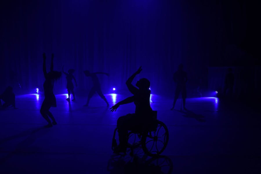 Dancers perform on a stage dimly lit in blue.