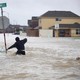 A person wades through high floodwaters.