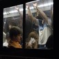A crowded bus captured from the outside, its many passengers framed by windows