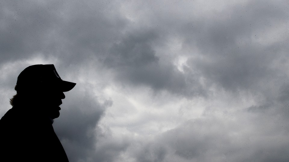 The silhouette of Donald Trump in front of a grey cloudy sky