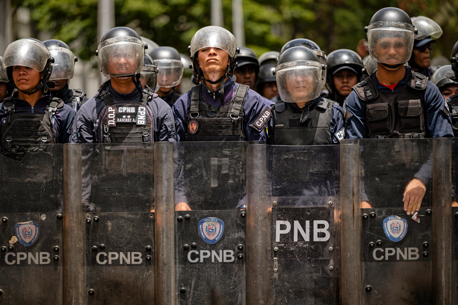 a line of Venezuelan security forces dressed in body armor and holding riot shields
