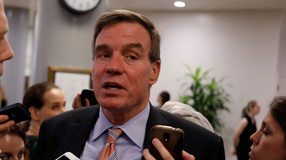 Mark Warner speaks as reporters hold up cellphones to record him.