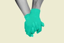 Two holding hands wearing green gloves