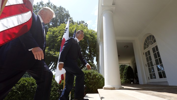 President Trump and South Korean President Moon Jae-in walk up the stairs of the rose garden with a U.S. and South Korean flag behind them.