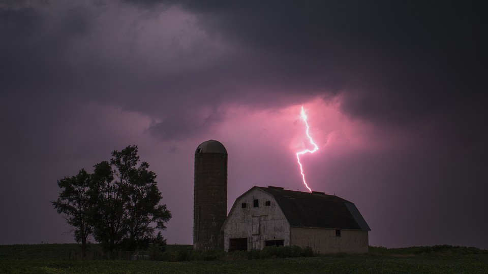 An image of a barn, with lightning striking over it. 