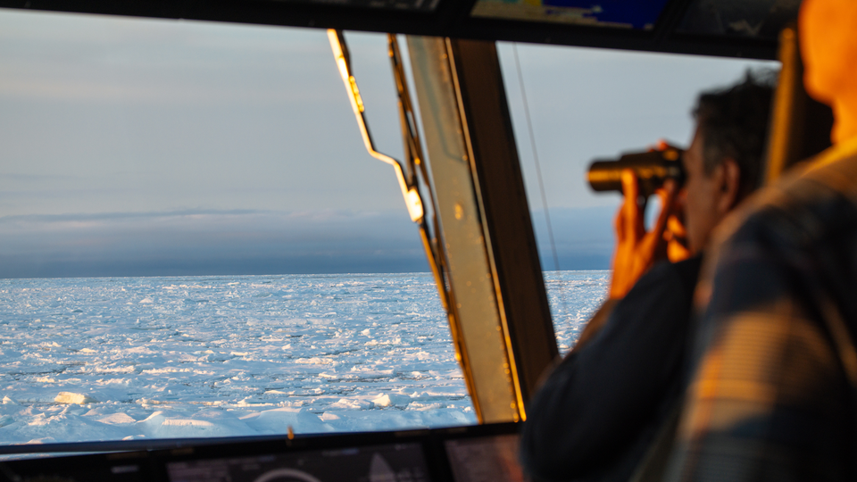 a man looks out the window at sea ice