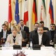 EU and Iranian delegates sitting at a table with flags behind them.