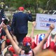 Trump is shown from behind at a campaign rally, raising his fist.