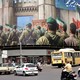 A large mural of Iranian soldiers looms over a commercial intersection in Tehran.