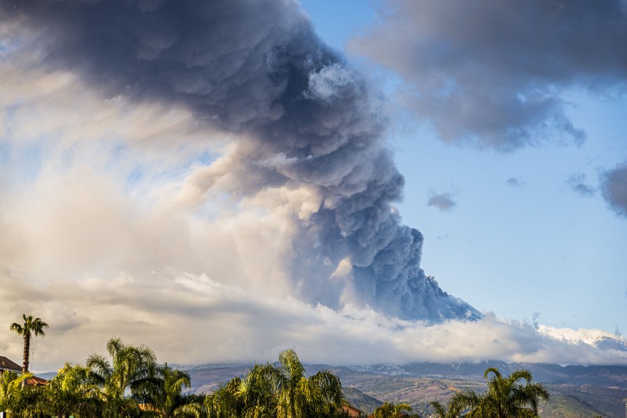 A large cloud of ash and volcanic gas rises above a volcano.