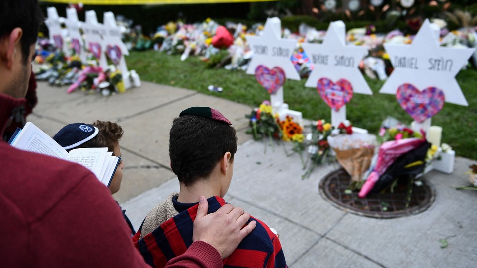 A man places his hand on the back of a boy while standing in front of a memorial.