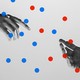 Two hands reaching toward each other, surrounded by blue and red dots
