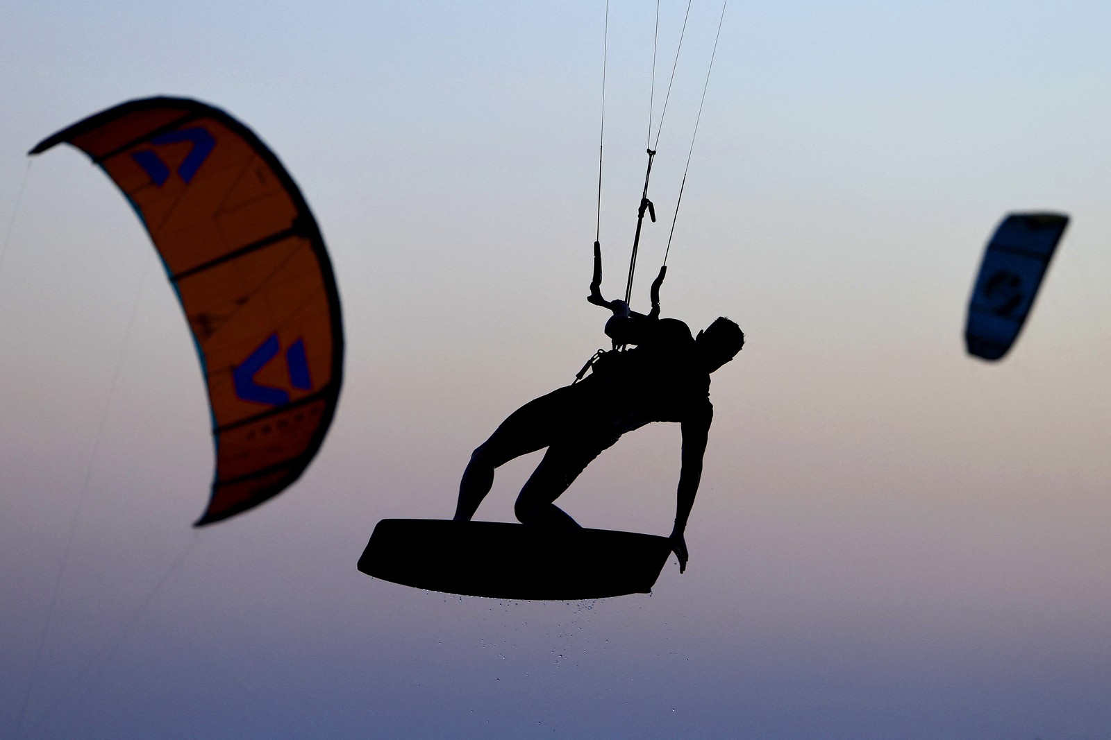 A kitesurfer, seen in the air, in silhouette