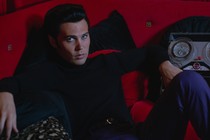 Austin Butler as Elvis Presley, lounging on a red couch in Baz Luhrmann's "Elvis"
