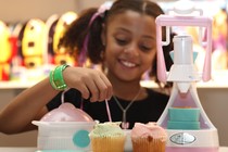 A girl poses with a cupcake-maker toy at the Dream Toys exhibition in London, in 2008.