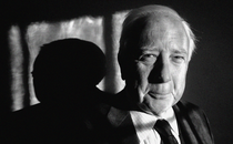 A black-and-white close-up photo of David McCullough from the shoulders up; he is wearing a suit and tie and smiling gently.