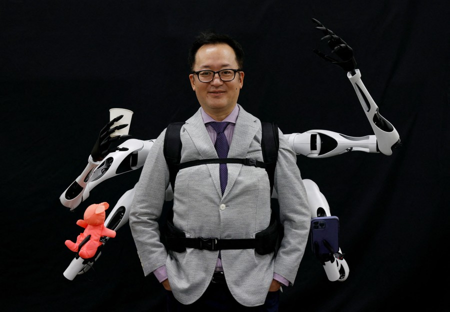 A person poses while wearing a set of four robotic arms.