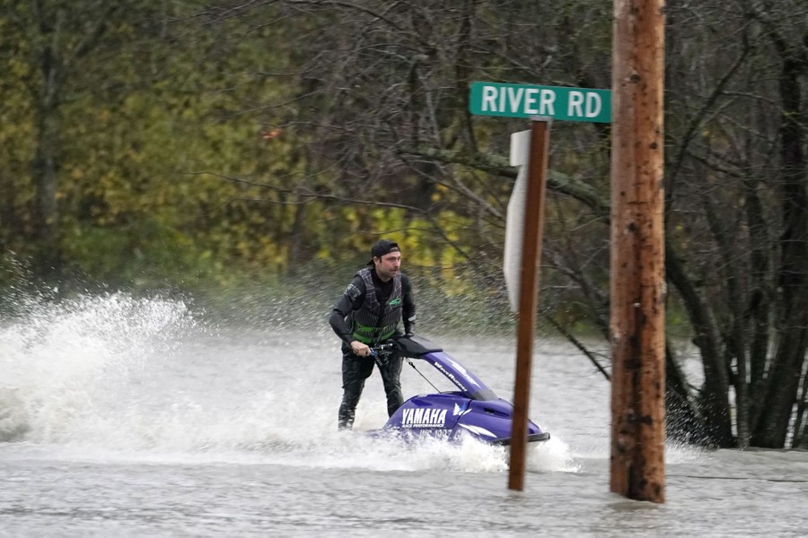 A man operates a personal watercraft along a flooded road.