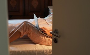 A person works on their laptop in bed.