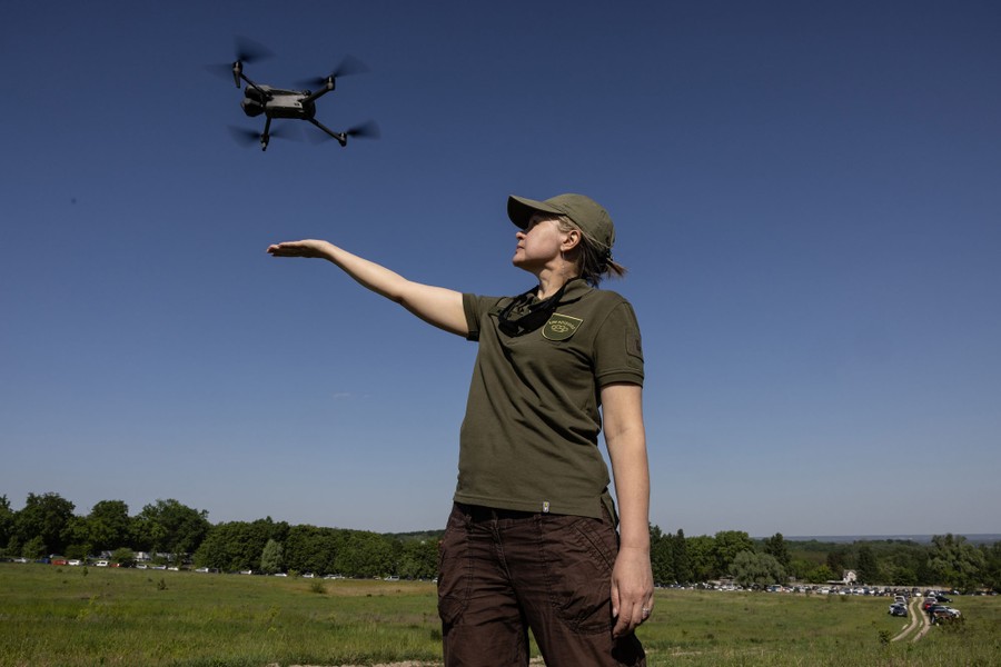 A person holds out their hand to release a small drone into the air.