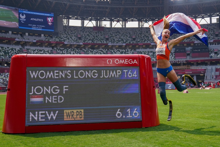 An athlete celebrates next to a scoreboard on a field.