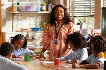 Quinta Brunson stands, smiling, at a classroom table where students are working in "Abbott Elementary"