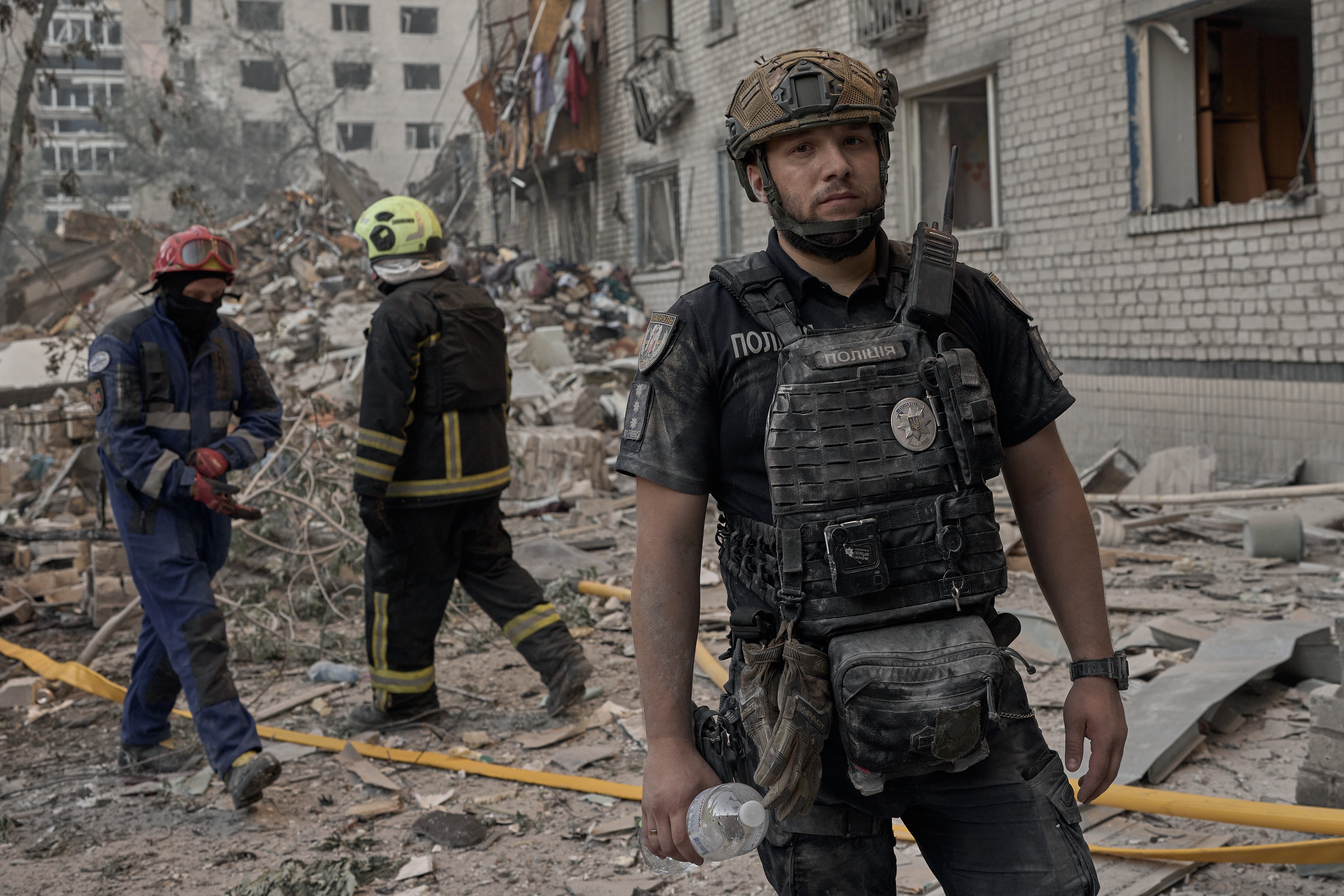 Several rescue workers operate at a destroyed section of a residential building after a missile strike.
