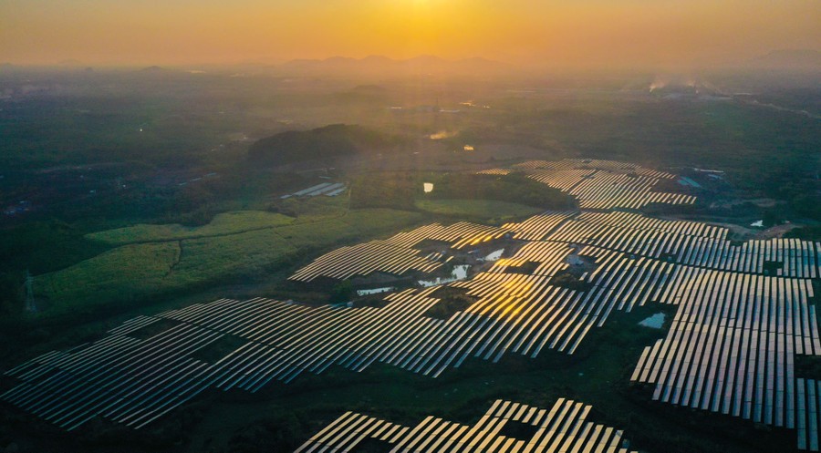 An aerial view of many rows of solar panels in a rural area