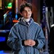 Actor Timothée Chalamet, wearing a blue-colored zip-up hoodie, stands with his hands clasped at his chest.