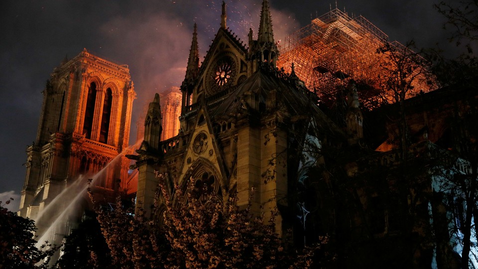 Sparks fill the air as Paris fire-brigade members spray water to extinguish flames as Notre-Dame Cathedral burns.