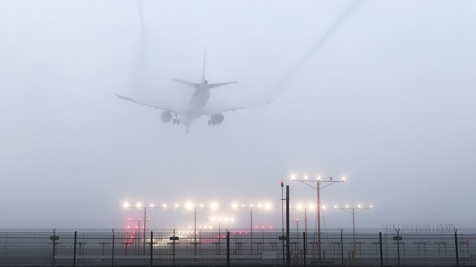 A plane landing on a foggy day