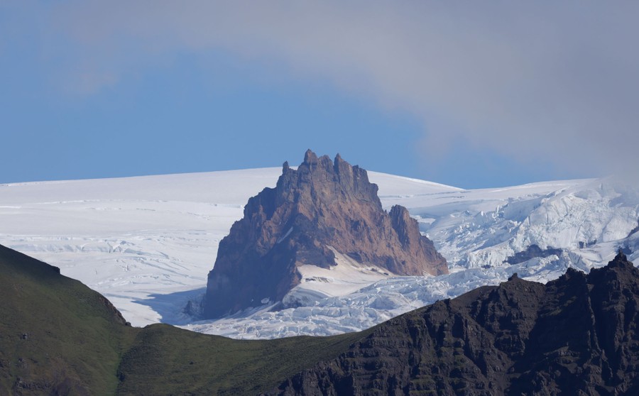A jagged mountain peak is seen poking up through ice and snow.