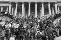 A black and white photo of a pro-Trump mob amassed outside the Capitol on January 6, 2021