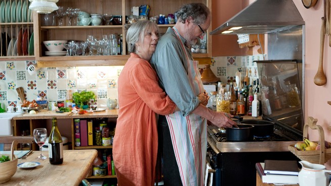 Jim Broadbent and Ruth Sheen embracing in a kitchen in 'Another Year'