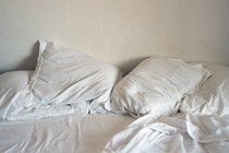 A picture of a bed with rumpled white sheets