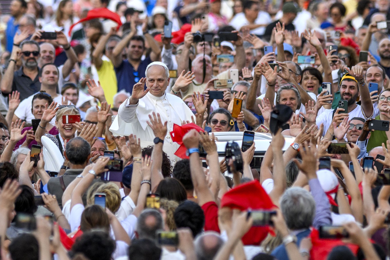 Pope Leo XIV waves to a crowd as he passes by in the popemobile.