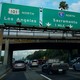 Morning traffic makes its way along a freeway interchange in Los Angeles. The traffic signs read Los Angeles, Sacramento, and Santa Monica.
