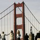 People gather on a hill in view of the Golden Gate Bridge