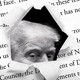Trump's eyes peeping through a rip in a printed Atlantic article about the attack plans shared on Signal
