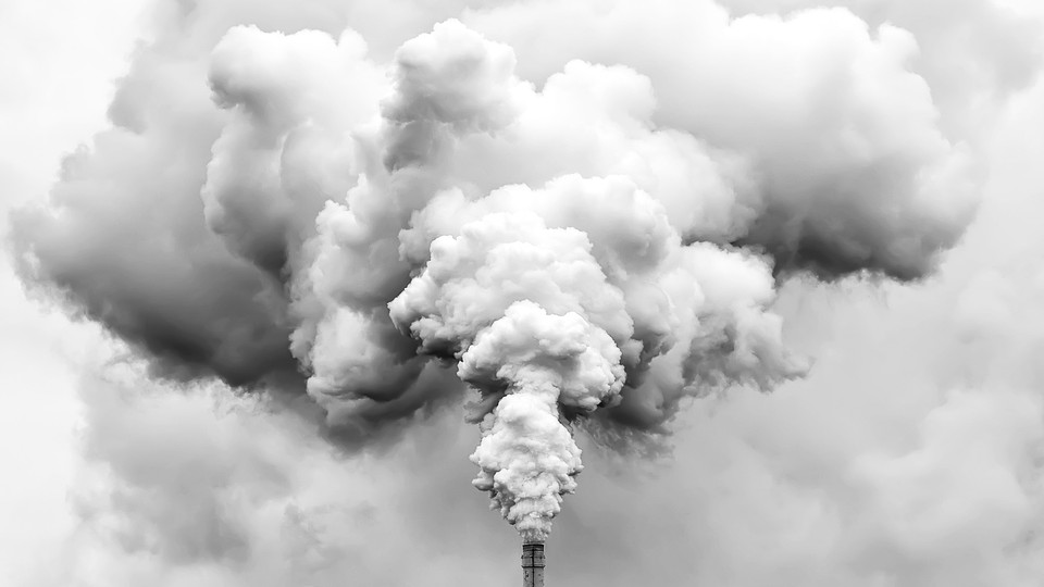 A smokestack billows vapor into a white sky