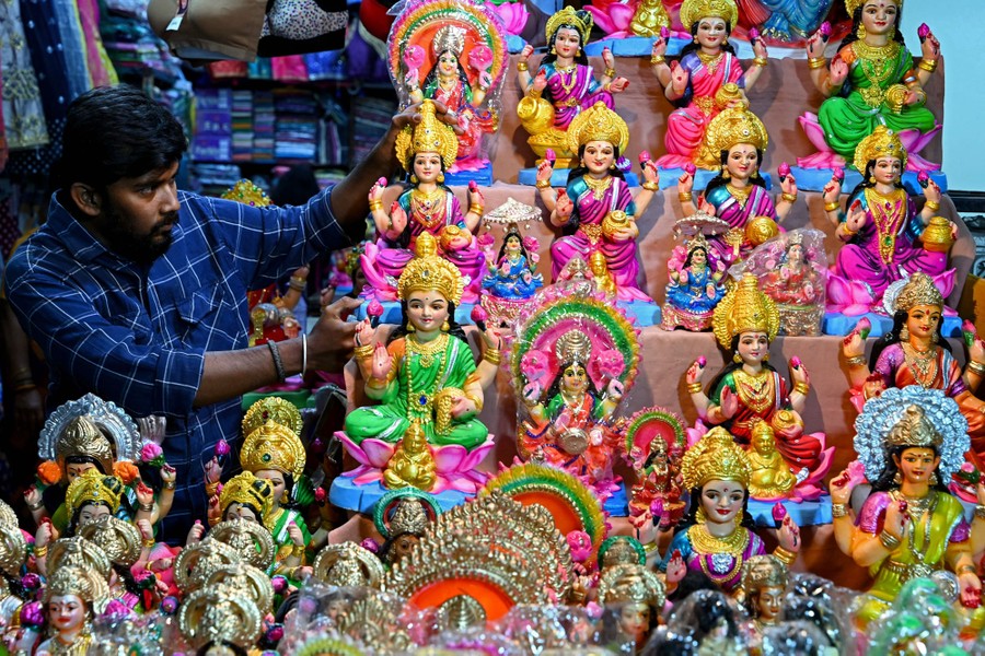 A seller adjusts miniature statues at a shop.