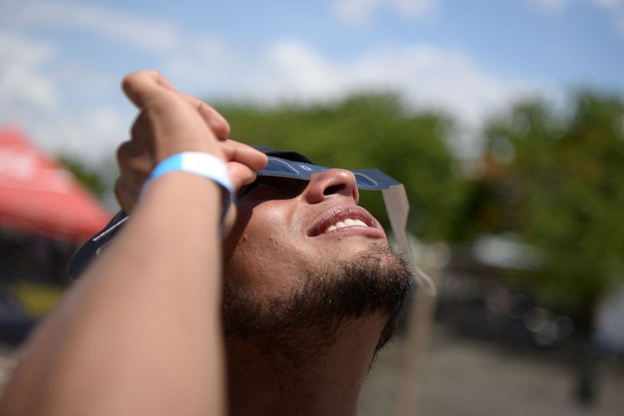 A person uses protective glasses, looking up at the solar eclipse.